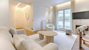 A modern living room with a sofa, a coffee table, and a TV. - Appartement de Luxe avec terrasse Champs Elysées (Paris)