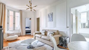 Een moderne woonkamer met een bank, stoelen, een salontafel en een bijzettafeltje van marmer.