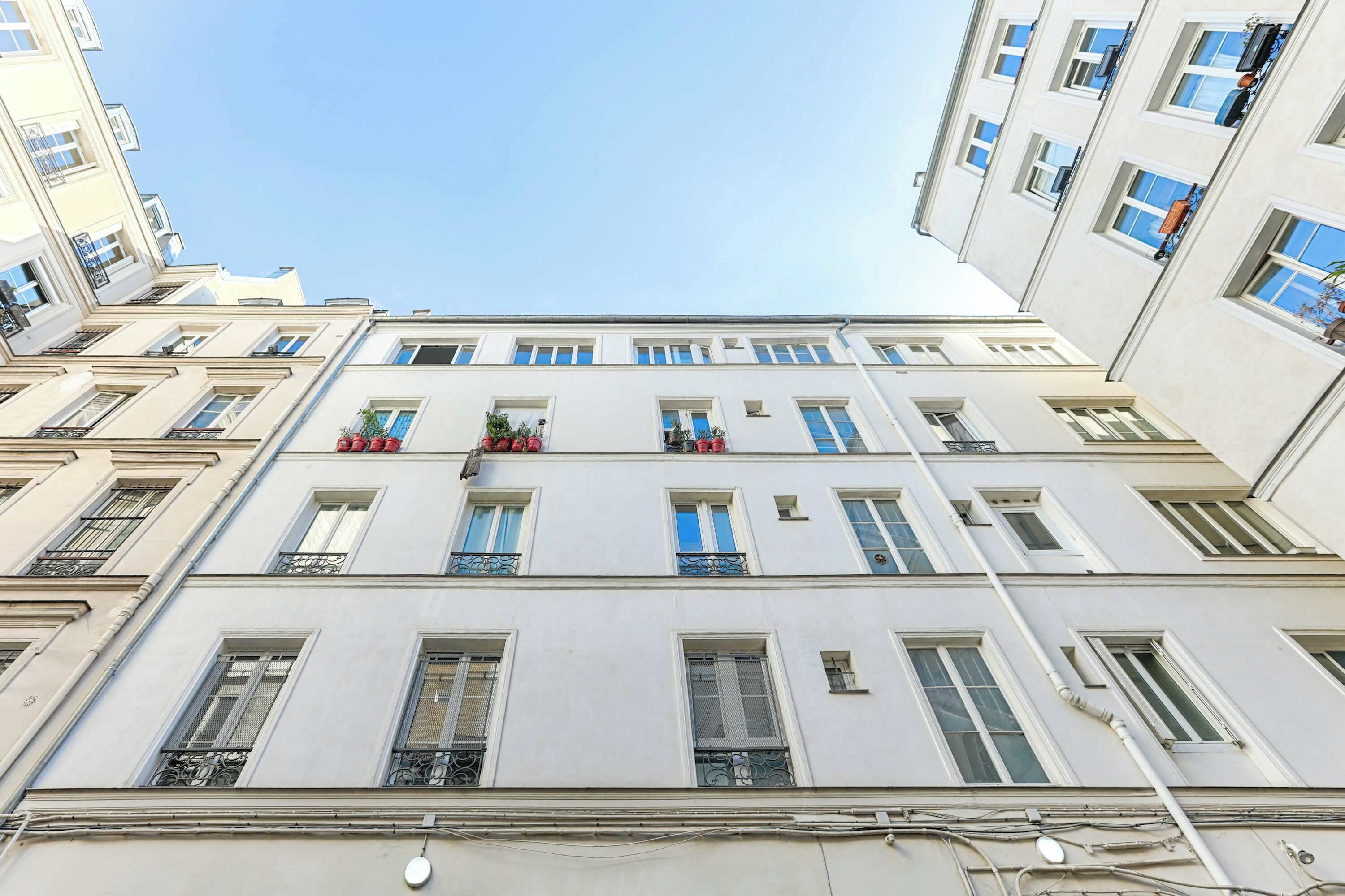 A multi-story building with balconies, large windows, and a clear sky.