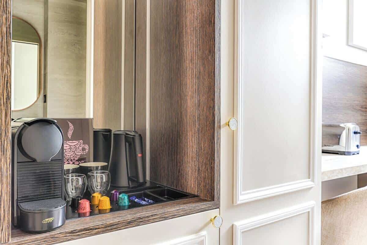 A hotel minibar with a coffee maker, tea kettle, and glasses.