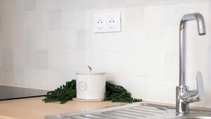 Een moderne keuken met witte kasten, een roestvrijstalen spoelbak en een wit aanrecht.