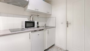 A kitchen with white cabinets, a microwave, a kettle, and a dishwasher. - Bastille/Republique Charming & Cosy Apartment 1BR (Paris)