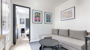 En moderne stue med sofa, rundt sofabord og billedkunst på væggene.