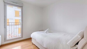 Une chambre à coucher avec un lit, une fenêtre et une vue sur les bâtiments environnants.
