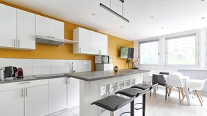 Una cocina moderna con armarios blancos, encimera gris y una barra con taburetes.