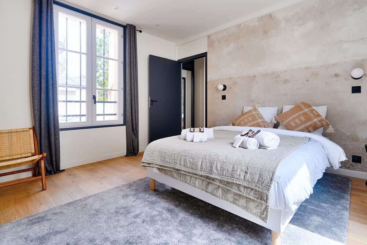 A bedroom with a bed, a bench, and a large window.