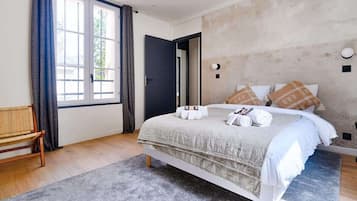 A bedroom with a bed, a bench, and a large window.