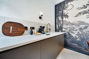 A modern bathroom with a large wooden vanity, a wall-mounted sink, and a mural of a landscape.