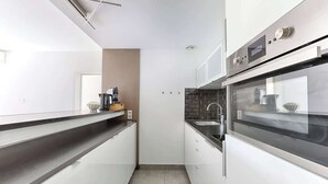 A modern kitchen with white cabinets, a black countertop, and stainless steel appliances.