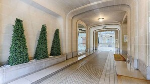 A corridor with tiled flooring, a bench, and three green planters. - Appartement de Luxe sur les Invalides (Paris)