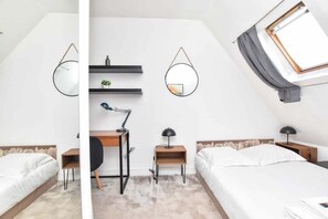 Un dormitorio moderno con dos camas, un escritorio y un tragaluz.