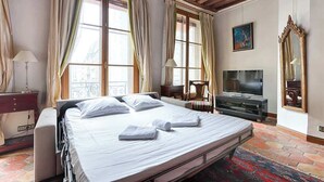 Ein Hotelzimmer mit Bett, Fernseher, Schreibtisch und einem Fenster mit Vorhängen.