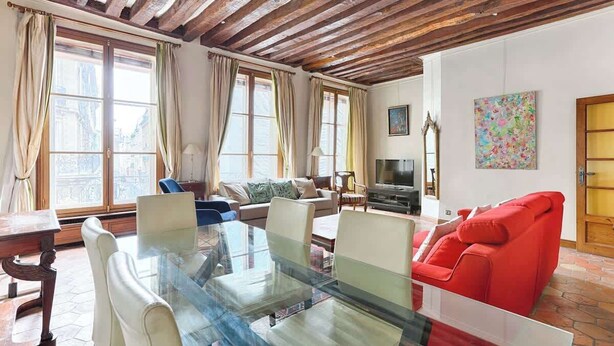 Ein geräumiges Wohnzimmer mit einem Glastisch, einem roten Sofa und einem Fernseher.