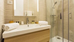 Une salle de bain moderne avec un grand lavabo, un miroir et une douche à parois de verre.