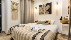 Une chambre d’hôtel avec un grand lit, une décoration murale en macramé et deux appliques murales.