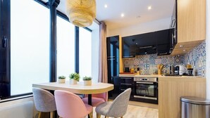 Une cuisine moderne avec une table de salle à manger ronde, des chaises et un petit îlot central doté d’un évier.