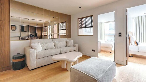 En moderne stue med sofa, sofabord og et stort vindue.