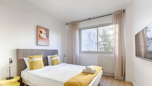 Une chambre bien rangée, avec un lit, une lampe de chevet et une fenêtre avec des rideaux.