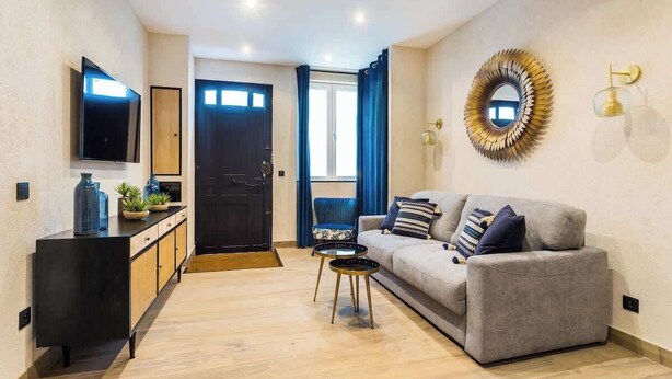 A modern living room with a grey sofa, a black cabinet, a TV, and a decorative mirror. - Nation/Charonne II : Magnifique Appartement 1BR-4P (Paris)
