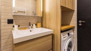A modern bathroom with a wooden vanity, a sink, a mirror, and a washing machine. - Nation/Charonne II : Magnifique Appartement 1BR-4P (Paris)