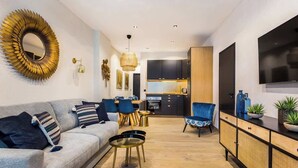 A modern living room with a grey sofa, a dining area, and a kitchen in the background. - Nation/Charonne II : Magnifique Appartement 1BR-4P (Paris)
