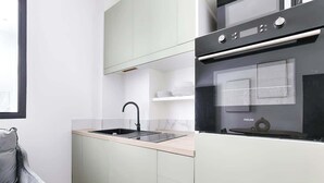 Une cuisine moderne avec des meubles de couleur vert clair, un four noir et un évier.