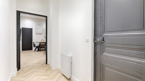 Un couloir avec un plancher en bois, un radiateur et une porte fermée.