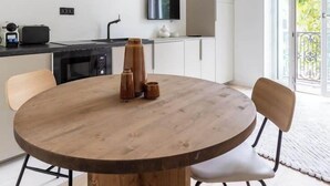 Eine moderne Küche mit einem runden Holztisch, zwei Stühlen und einem an der Wand befestigten Fernseher.
