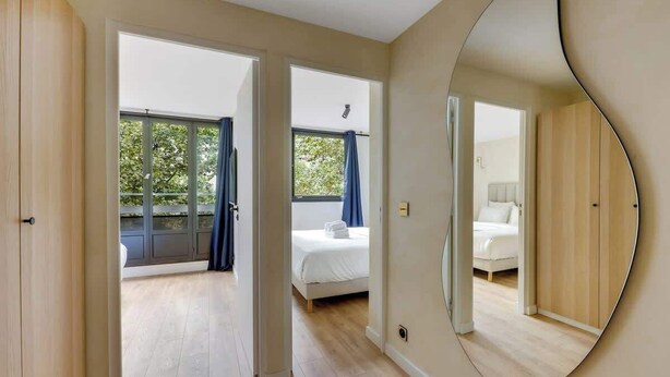 Una camera da letto moderna con uno specchio grande, un letto e vista all'esterno tramite una porta scorrevole.