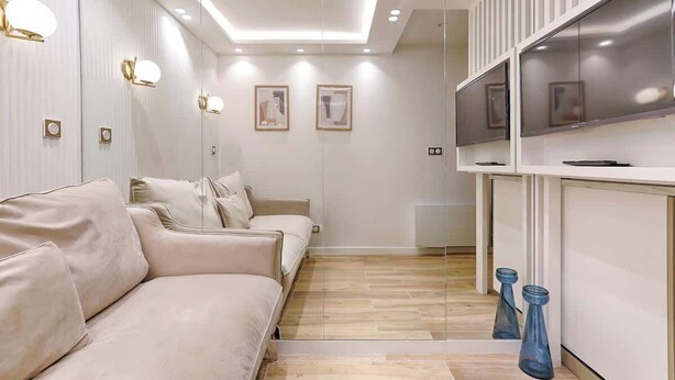 Ett modernt hotellrum med en soffa, en TV och ett litet köksutrymme.