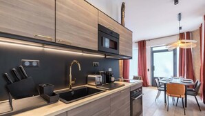 Eine moderne Küche mit Einbauofen, Mikrowelle und Spüle. Ein Essbereich mit Tisch und Stühlen ist ebenfalls vorhanden.