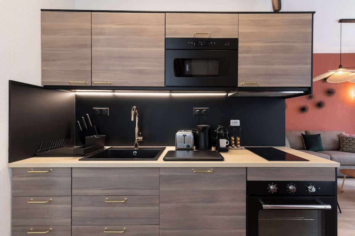 A modern kitchen with a built-in oven, microwave, and a coffee machine.