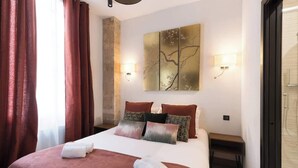 Ein Hotelzimmer mit einem großen Bett, roten Vorhängen, einem Wandbild und einem Nachttisch.