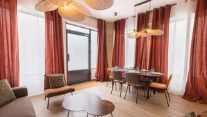 Ein modernes Wohnzimmer mit Essbereich, ausgestattet mit einem großen Fenster, roten Vorhängen und zeitgemäßen Möbeln.