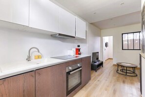 Una cocina moderna con armarios blancos, un lavamanos de acero inoxidable y un horno empotrado.