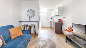 A modern living room with a blue sofa, a wooden coffee table, and a TV. - Appartement Cosy au cœur de Batignolles (Paris)