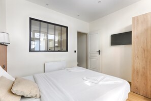 Un dormitorio con cama, espejo, televisión y armario.