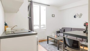 Um espaço compacto com cozinha compacta, área de refeições e sofá.