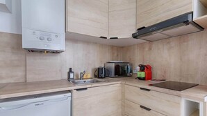 A compact kitchen with a dishwasher, microwave, and a coffee machine. - Laugier Ternes : Appartement Cosy en Bail Mobilité (Paris)