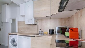 A compact kitchen with a washing machine, a sink, and a stove. - Laugier Ternes : Appartement Cosy en Bail Mobilité (Paris)