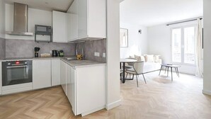 Een moderne keuken met witte kastjes, een ingebouwde oven en een magnetron.
