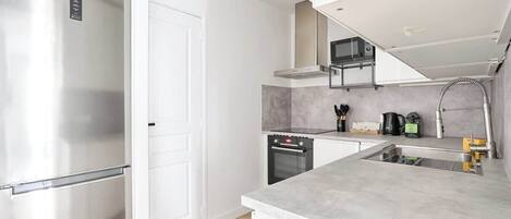 Una cocina moderna con electrodomésticos de acero inoxidable, un microondas y un lavamanos.