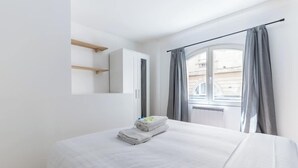 A bedroom with a bed, a window with curtains, a wardrobe, and a mirror. - Marivaux/Opéra : Charming & Cosy Duplex 4P-1BR (Paris)