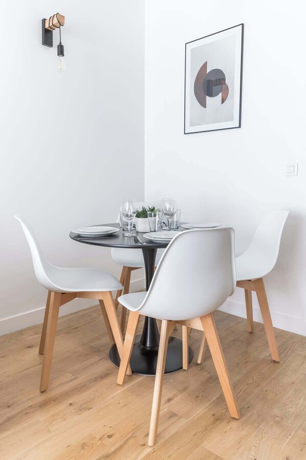 A dining area with a round table, white chairs, and a modern light fixture.