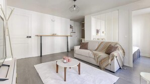Una sala de estar moderna con un sofá blanco, una mesa de centro y un comedor con una mesa y sillas de madera.