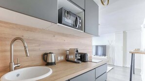 Una cocina moderna con encimera de madera, un lavamanos, una cafetera y un hervidor.