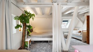 Ein Zimmer mit einem Etagenbett, einem kleinen Tisch, einer Pflanze und einem Fenster mit Vorhängen.