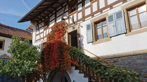 Ein traditionelles Fachwerkhäuschen mit Treppe, Steinmauer und einem kleinen Garten.