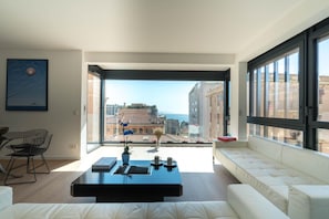 A modern living room with a large window, a sofa, a coffee table, and a chair.