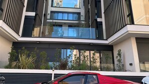 Een modern gebouw met een rode sportauto ervoor geparkeerd.